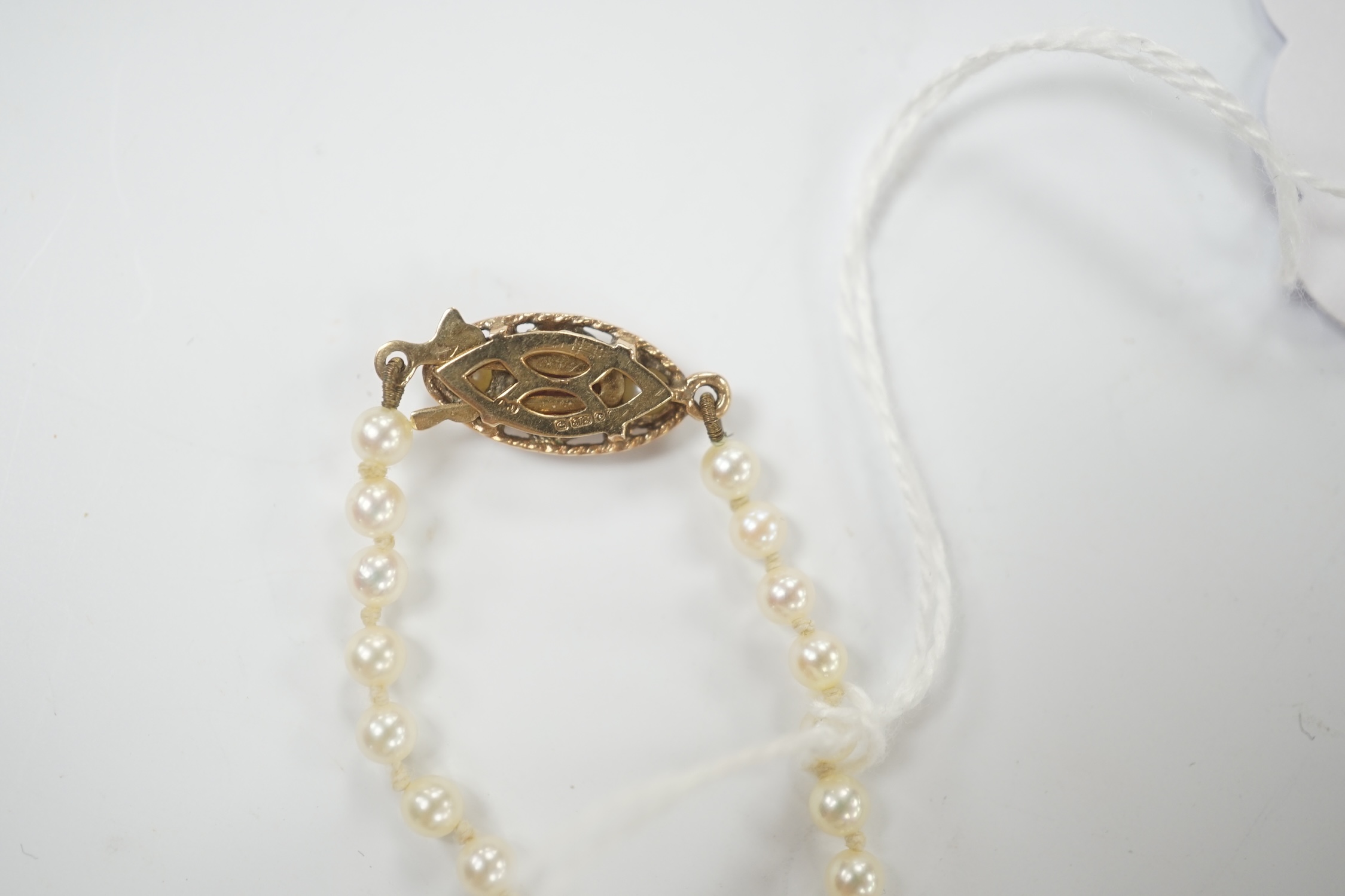 A single strand graduated cultured pearl necklace, with garnet and seed pearl set 9ct gold clasp, 52cm.